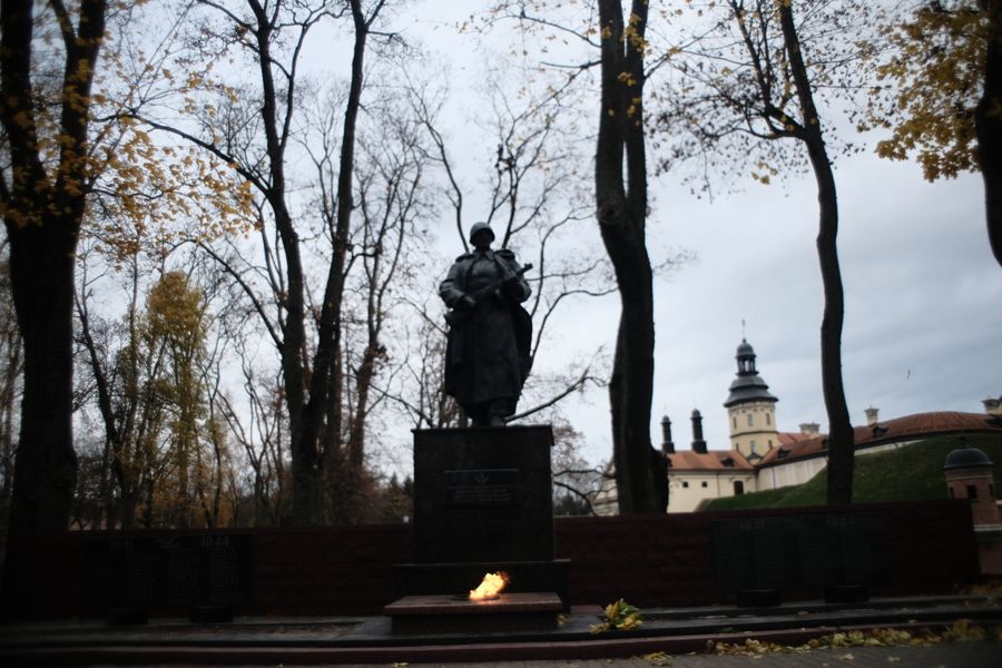 Памятник среди деревьев, рядом с замковыми стенами. 1 ноября 2024.