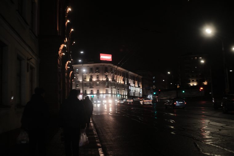 Огни здания отражаются на мокром асфальте. Минск ночью.