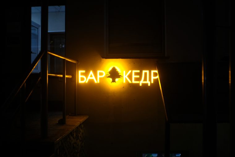 Жёлтая вывеска «Бар Кедр» в тёмном городском проходе. Минск.